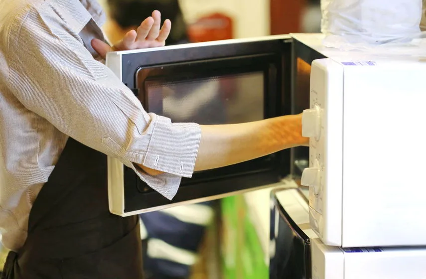 Arm Picking Up Food From Inside Microwave Oven