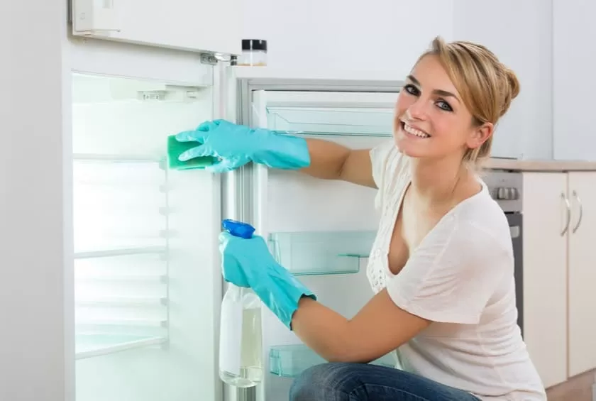 Happy Young Woman Cleaning Refrigerator At Home