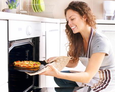 Happy Young Woman Cooking Pizza in Gas Oven