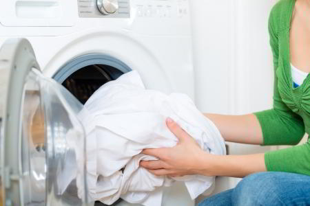 Housekeeper Taking Laundry Out Of Gas Dryer