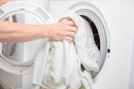 Lady Filling Clothes Dryer With Linen