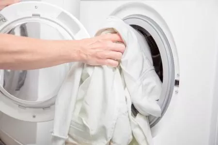 Lady Filling Clothes Dryer With Linen