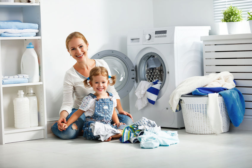 Mother And Child In Laundry Room Near Washing Machine And Dirty Clothes