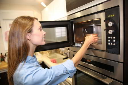 Woman Heating Dish In Microwave