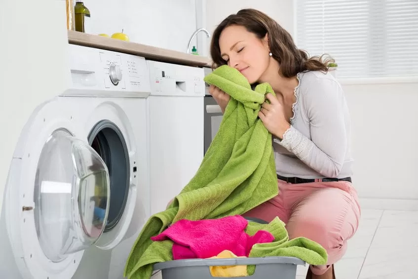 Young Woman With Washed Clothes Near Washing Machine